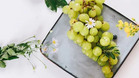 Still life, table setting, beautiful, plate with green grapes, white flowers, Stock Footage 278436014