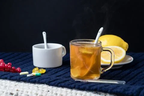 Still life of tea with lemon, tablets and thermometer, jam and berries. The c Foto stock