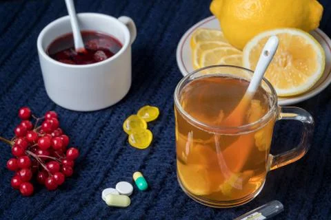 Still life of tea with lemon, tablets and thermometer, jam and berries. The c Stock Photos