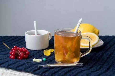 Still life of tea with lemon, tablets and thermometer, jam and berries. The c Stock Photos