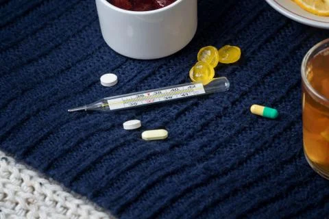 Still life of tea with lemon, tablets and thermometer, jam and berries. The c Stock Photos