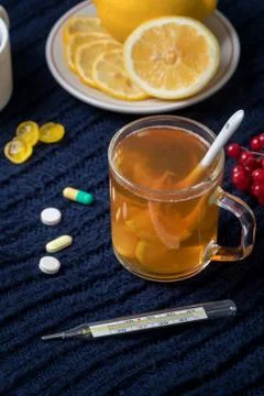 Still life of tea with lemon, tablets and thermometer, jam and berries. The c Stock Photos