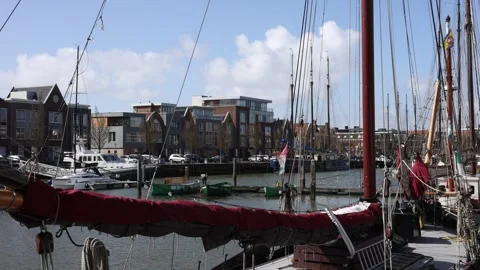 Still masts and flag above canal houses in harbor Stock Footage 331839387