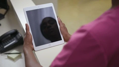 Still, over the shoulder shot of iPad, tablet held by female nurse, pink scrubs Stock Footage 109503980