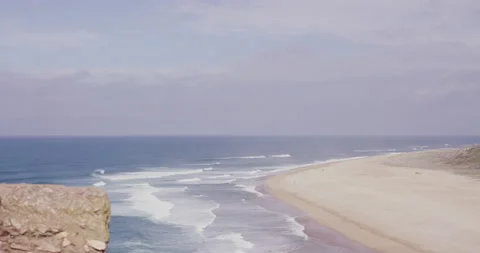 Still shot of blue ocean with waves splashing on sandy beach during sunny day Stock Footage 158648247