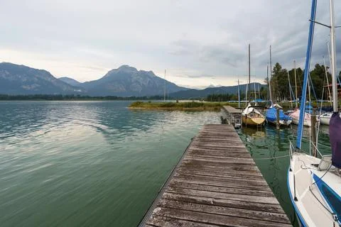 Still waters of Walchensee on an overcast day, sailboats gently bobbing nex.. Stock Photos