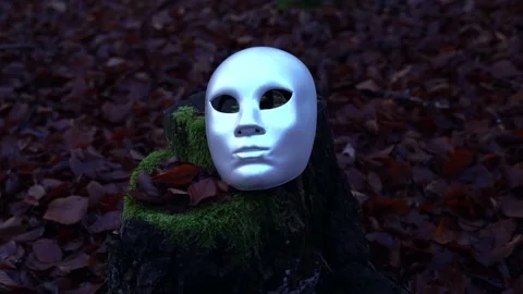 Still of white mask on tree trunk with moss and brown leaves Stock Footage 134828501