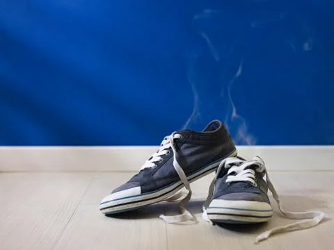 Stinking worn-out shoes left on wooden floor Stock Photos