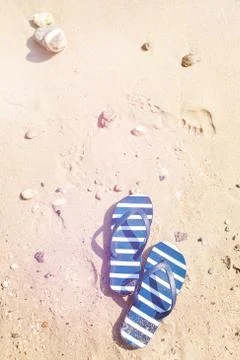 Stiped flip flops on the sand. Stock Photos