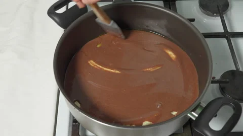 Stir the cocoa chocolate mixture in a hot pan with fried bananas. Cooking a cake Stock Footage 232624345