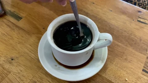 Stir a cup of black coffee before drinking Stock Footage 234577753