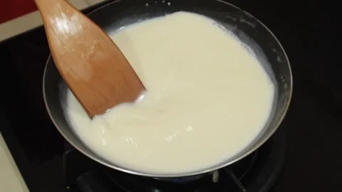 Stir the flour mixture in the pan. Someone cooks coconut milk Stock Footage 334647580
