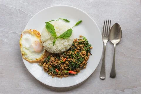 Stir fried basil with minced pork and fried egg on white table top view. Stock Photos