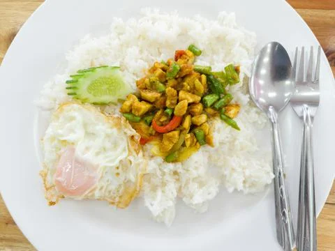 Stir fried chicken curry paste with lentils over rice and cucumber and fried Stock Photos