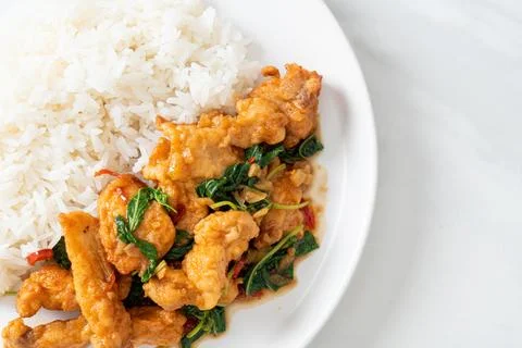 Stir-fried fried fish with basil and chili in thai style topped on rice Stock Photos