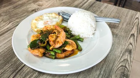 Stir-fried shrimp with chili paste over steamed rice on a white plate on a .. Stock Photos