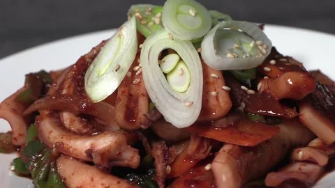 Stir-fried spicy squid on a white plate. Video stock 293748498