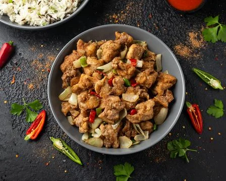 Stir fry chinese salt and pepper chicken with rice in grey bowl Stock Photos