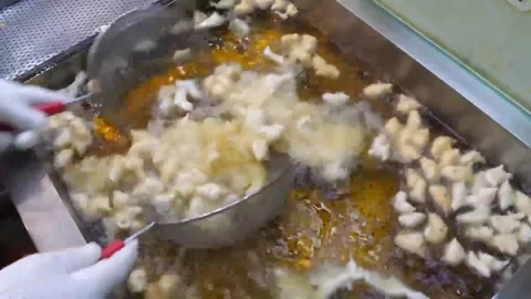 Stir-frying fresh squid eggs in a large pan at a vibrant Asian street food marke Stock Footage 337374765