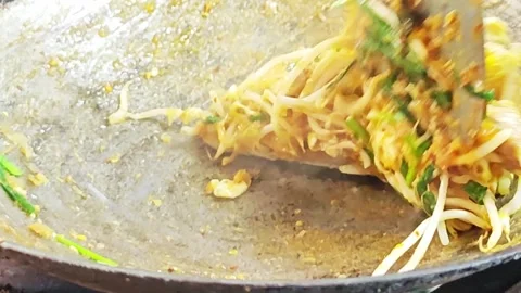 Stir-frying Pad Thai with bean sprouts and chives in a wok. Stock Footage 342402892