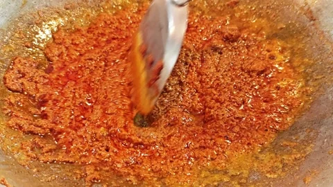 Stir-frying Thai red curry paste in a hot wok. Vidéo 344560245