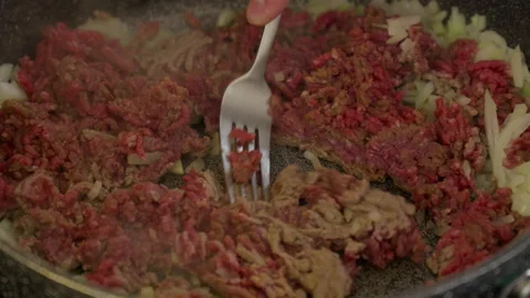 Stir hash brown beef meat dropped on top of diced onion in in gray frying pan Vídeo Stock 266783317