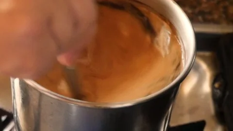 Stiring a hot pot of coffee, while its still on the Stock Footage 125780068
