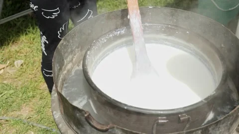 Stirring and warming milk to make white feta cheese dairy products Stock Footage 193364734