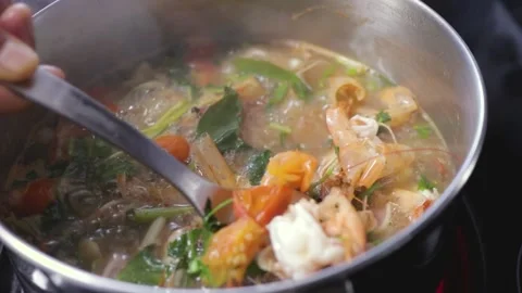 Stirring authentic tom yum soup, shrimp prawns Thai herbs in Thai cooking pot Stock Footage 155308404