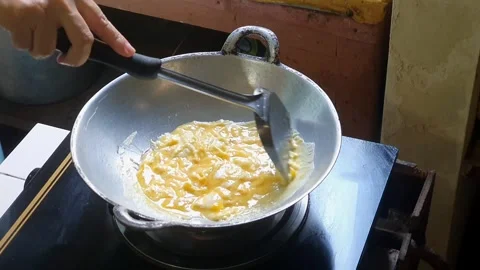 Stirring beaten eggs or whisked egg in the frying pan on the lit stove with.. Stock Footage 279294535