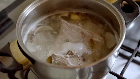 Stirring boiling chicken and meat in pot on gas stove during cooking Stockbeeldmateriaal 333682058