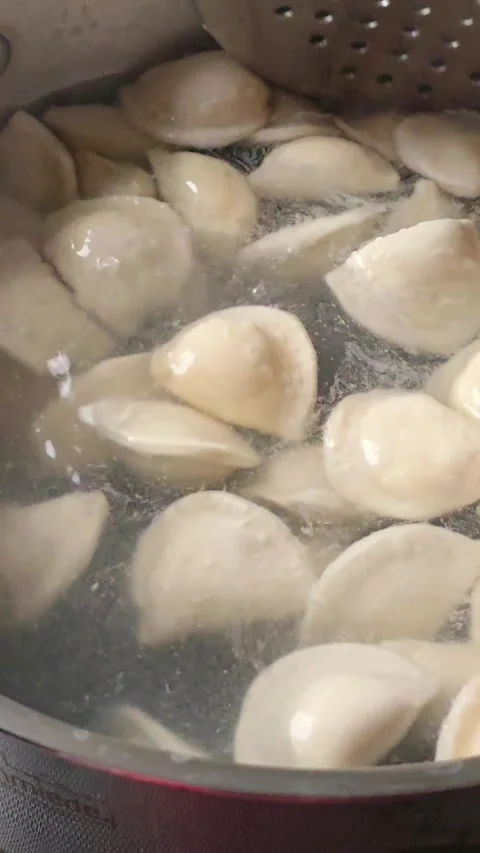 Stirring Boiling Dumplings in a Pot with a Slotted Spoon 動画素材 345453927