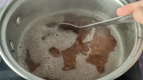 Stirring buckwheat with a spoon in boiling water in a saucepan Stock Footage 231594064