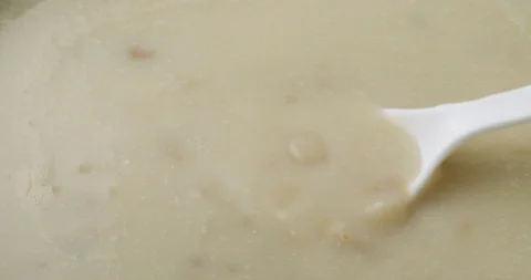 Stirring canned clam chowder with a white spoon Stock Footage 101995333