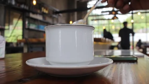 Stirring Coffee in a White Cup at a Cafe with a Spoon for a Relaxing Break. Stock Footage 303952850