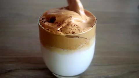 Stirring a cup of whipped coffee by spoon. Coffee latte stirring on table. 動画素材 150112486