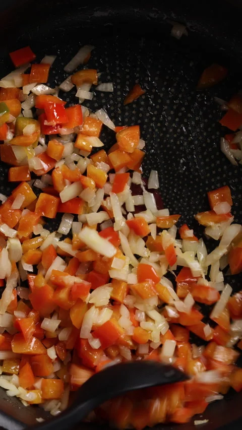 Stirring Diced Onion and Red Bell Pepper in Pan Extreme Close Up Vertical Vidéo 336575986