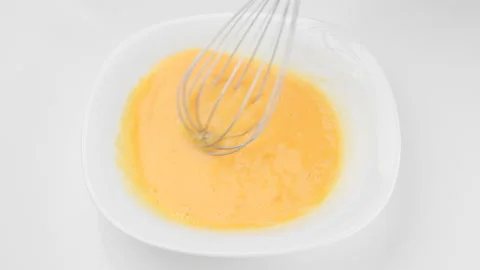 Stirring eggs with whisk, isolated on white background 스톡 동영상 221394017