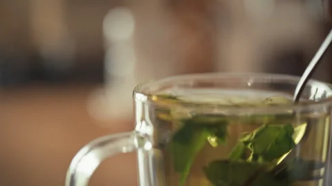 Stirring fresh herbal tea in a cozy setting during a relaxing afternoon Stock Footage 323926448