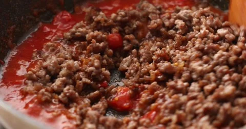 Stirring the fried minced meat and tomato sauce in a frying pan. Stock Footage 249663993