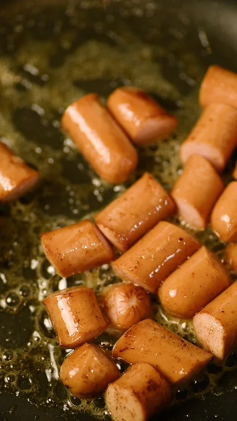 Stirring fried sausage slices inside a hot frying pan 库存影片 344891756