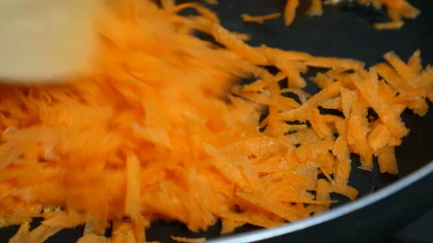 Stirring grated carrots while frying in the pan Stock Footage 86599656