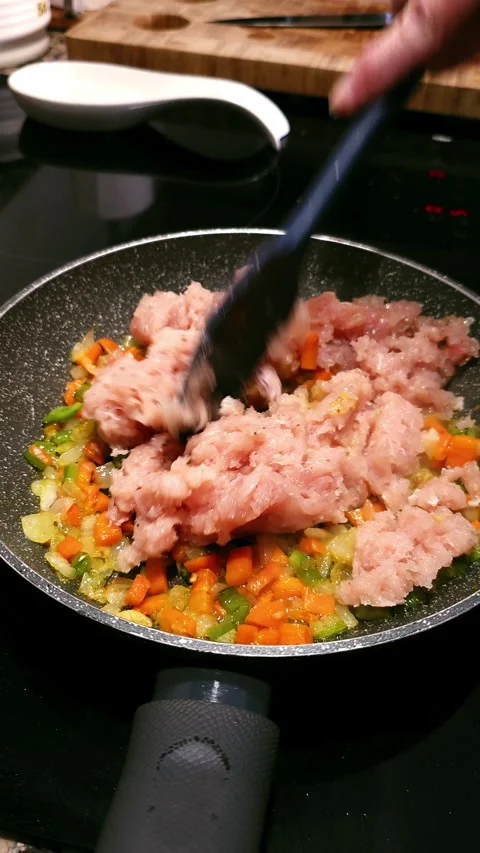 Stirring ground chicken with vegetables in hot olive oil. 動画素材 346068441