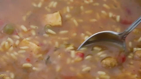 Stirring gumbo with a spoon while heating Stock Footage 75649615