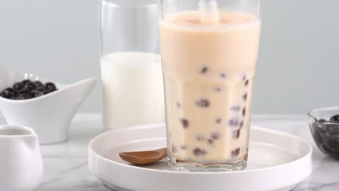 Stirring homemade tapioca pearl bubble milk tea in drinking glass, 4K. Stock Footage 112696072