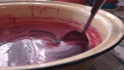 Stirring hot freshly brewed raspberry jam with foam in a large enameled bowl Stock Footage 131334997
