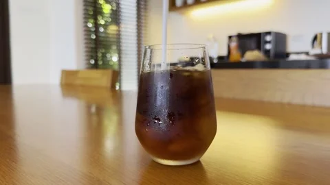 Stirring Iced Black Coffee Straw Glass Close Up  Wooden Table 4K HDR Lifestyle Stock Footage 335698143