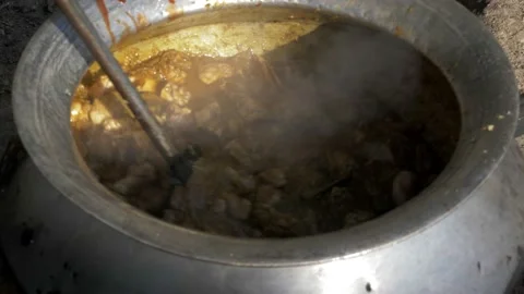 Stirring a large pot while cooking outdoors for a big event in the village Stock Footage 152977441