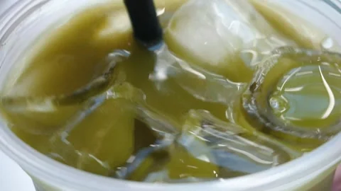 Stirring matcha ice tea latte with plastic straw. Video stock 280155698