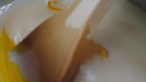 Stirring Melted Orange and White Candy Coating with Wooden Spatula Stock Footage 345292025